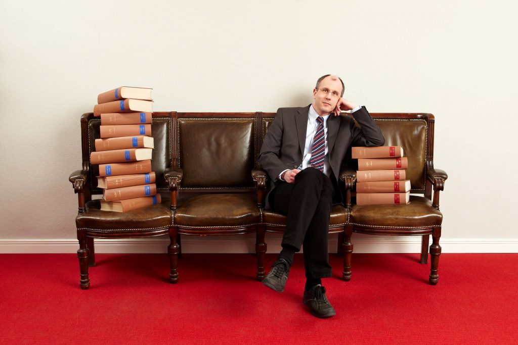 Anwalt mit Büchern auf einem Ledersofa - Businessfoto