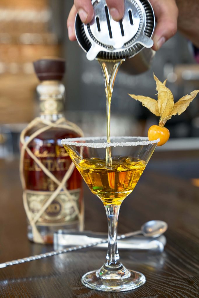 Barkeeper schenkt Drink in Martini-Glas ein: Foodfotografie