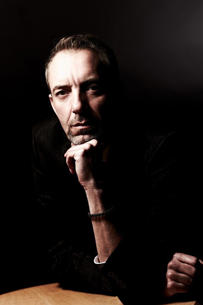 Autor in schwarzem Hemd im Schatten: Portraitfoto