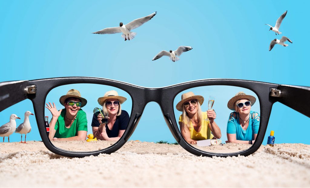 Personen am Strand blicken durch gigantische Sonnenbrille: Konzept für Werbefotografie