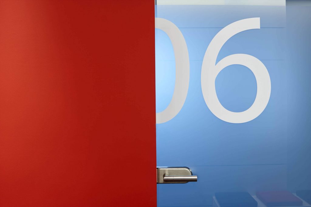 Tür aus Milchglas mit der Aufschrift 06 neben roter Wand für Businessfoto