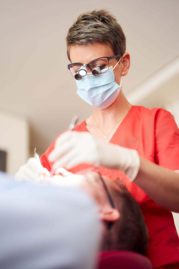 Zahnärztin behandelt einen Patienten für Businessfotografie